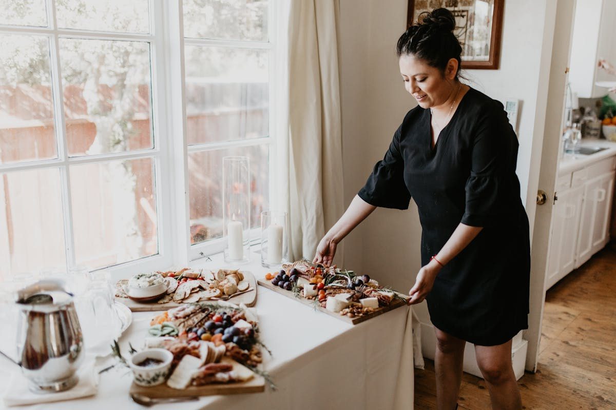 A grazing board being arranged with creamery cheeses, house charcuterie, and garden crudité